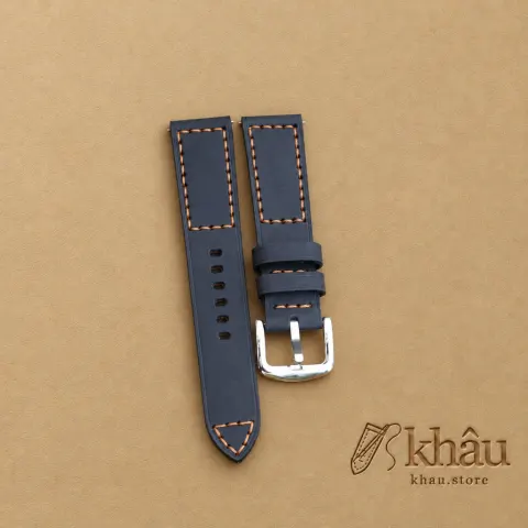 Navy cowhide watch strap with tan hand stitching and a silver-tone buckle — partner workshop photograph