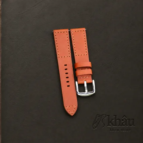 Cognac cowhide watch strap with tan hand stitching and a silver-tone buckle — partner workshop photograph