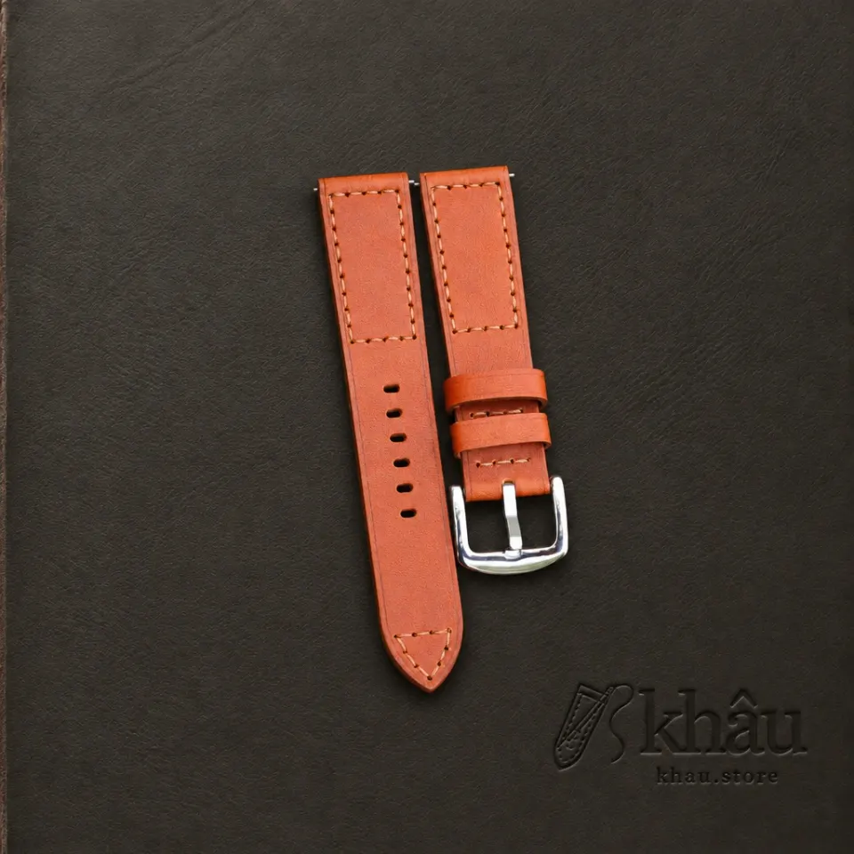 Cognac cowhide watch strap with tan hand stitching and a silver-tone buckle — partner workshop photograph