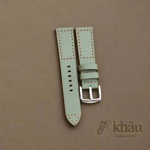 Sage cowhide watch strap with tan hand stitching and a silver-tone buckle — partner workshop photograph