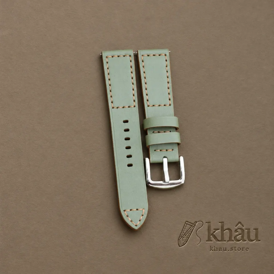 Sage cowhide watch strap with tan hand stitching and a silver-tone buckle — partner workshop photograph