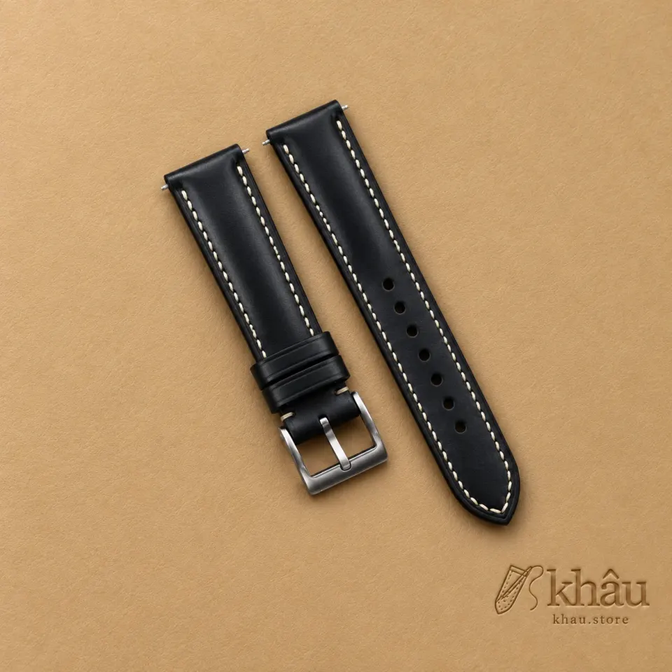 Black Buttero Leather Watch Strap with Khâu debossed branding on a warm tan background
