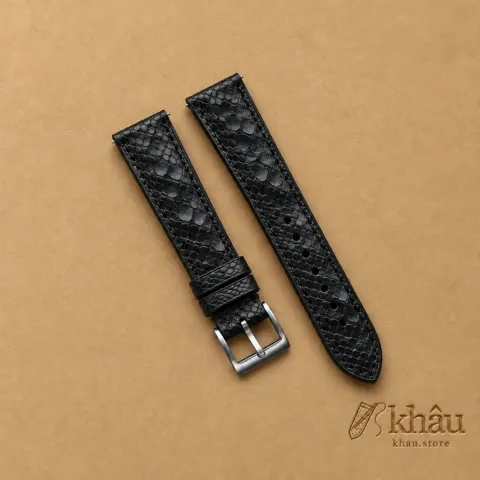 Black Python Leather Watch Strap with Khâu debossed branding on a warm tan background