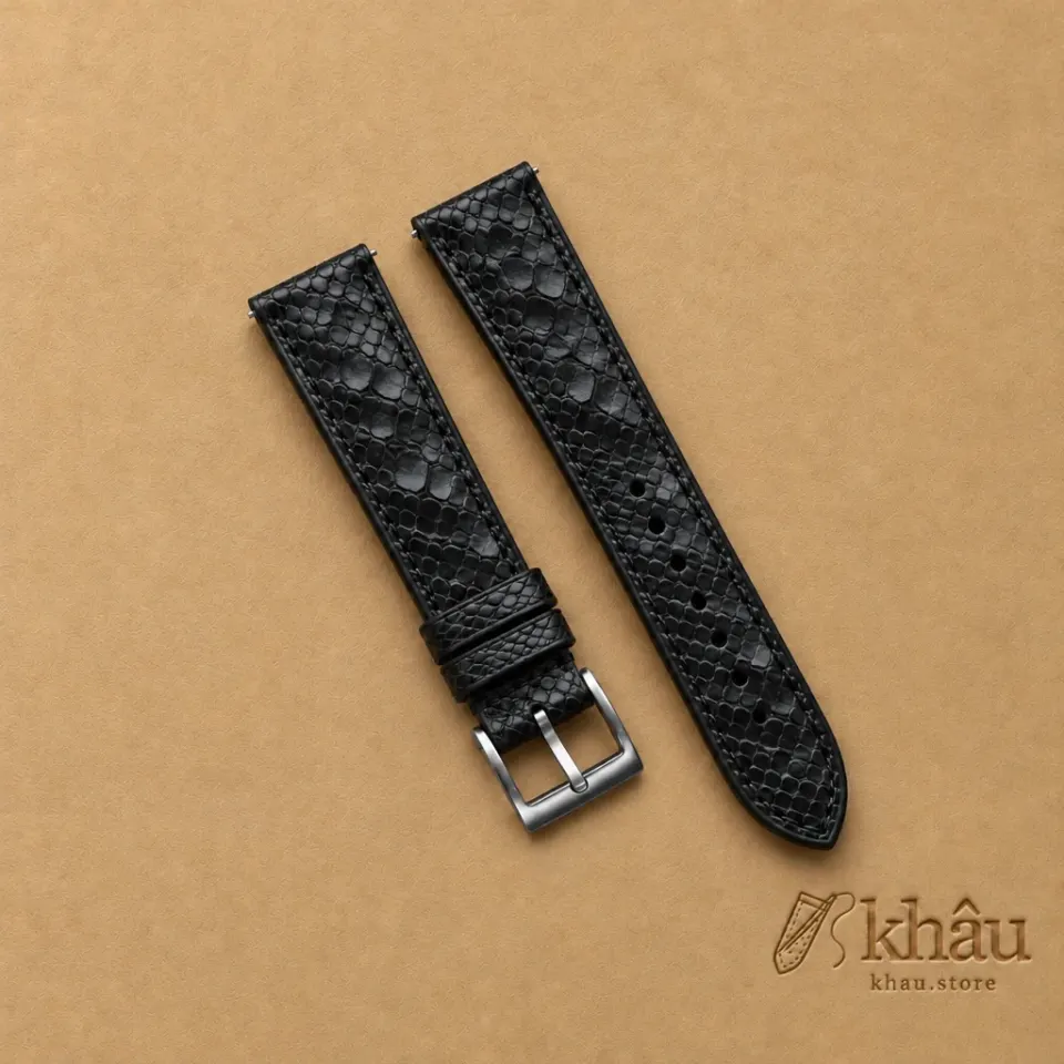 Black Python Leather Watch Strap with Khâu debossed branding on a warm tan background