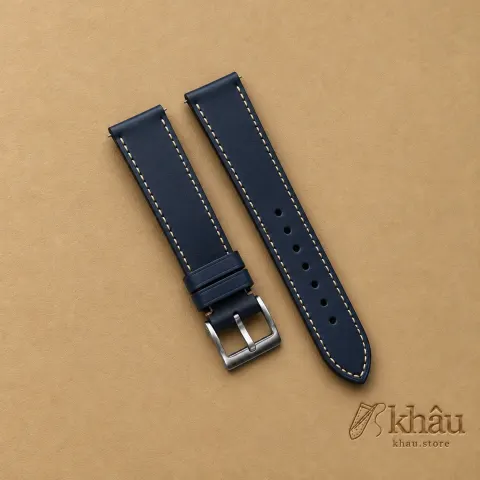 Navy Buttero Leather Watch Strap with Khâu debossed branding on a warm tan background
