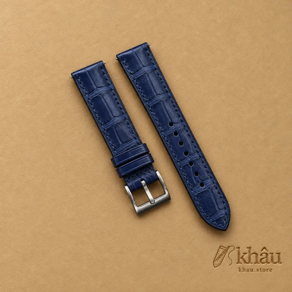 Nightwater Blue Alligator Watch Strap with Khâu debossed branding on a warm tan background