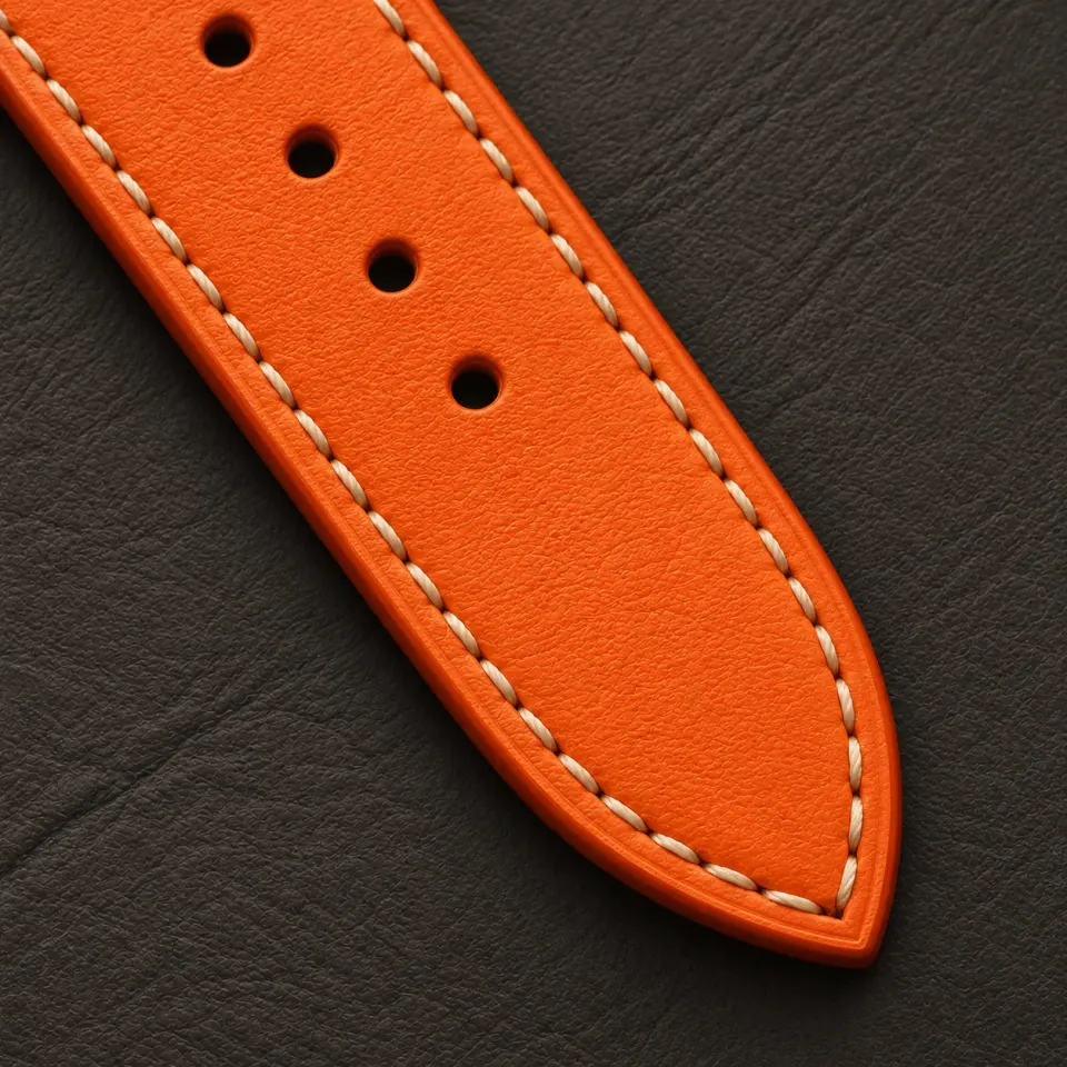 Close detail of the orange cowhide, ivory hand stitching and finished edge